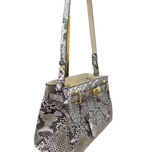 May include: A white ceramic mug with a black handle and the text "But First, Coffee" in a handwritten style. The mug is on a white surface. The mug is 10 cm tall.