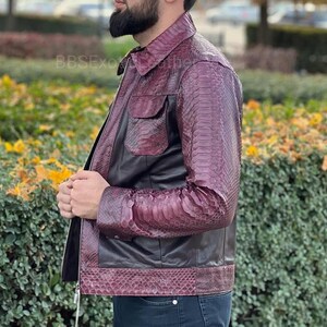 May include: A burgundy and black leather jacket with a snakeskin pattern on the sleeves and lower section. The jacket features a zip closure, two front pockets, and a collared neckline. The brand name "BBSEXO" is visible on the upper left.