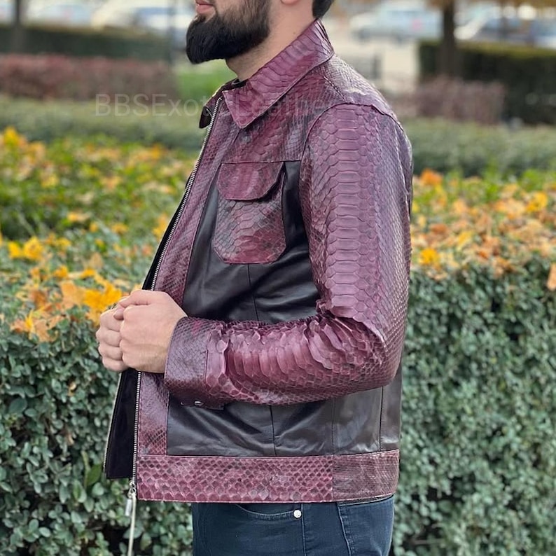 May include: A burgundy and black leather jacket with a snakeskin pattern on the sleeves and lower section. The jacket features a zip closure, two front pockets, and a collared neckline. The brand name "BBSEXO" is visible on the upper left.