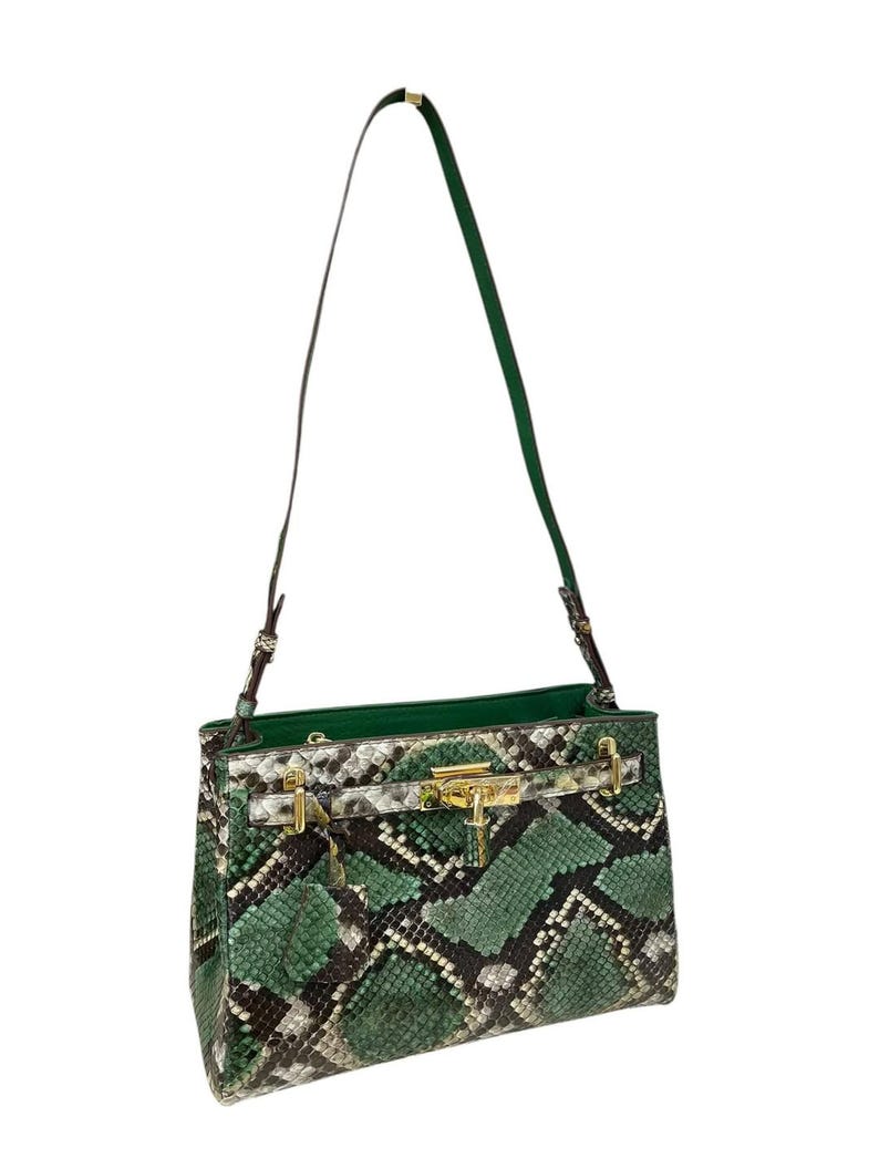 May include: A green and brown snakeskin-effect handbag with gold-tone hardware and a long, green strap. The bag features a structured design and a gold clasp. The interior is green.