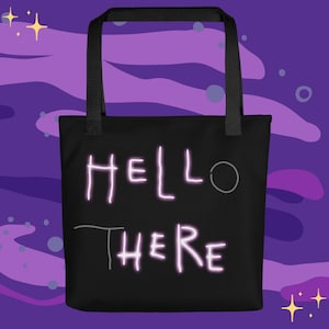 Puede incluir: Bolso tote negro con las palabras "HELLO THERE" en una fuente de estilo neón. El bolso tiene asas negras y está sobre un fondo morado con estrellas y círculos.