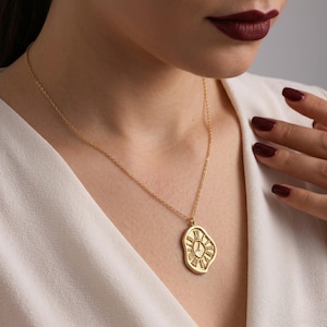 May include: A gold-colored necklace with a pendant shaped like a melting clock. The pendant features Roman numerals and hands indicating the time. The necklace is worn against a white blouse.