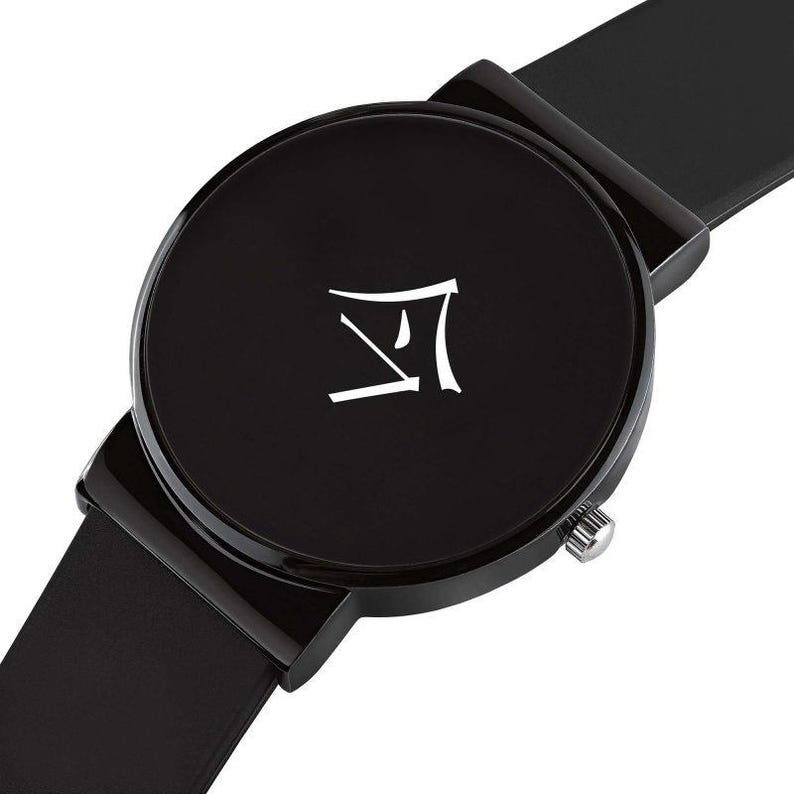 Puede incluir: Reloj de pulsera negro con esfera redonda y correa negra. La esfera del reloj presenta un s&iacute;mbolo blanco. El reloj tiene una corona plateada. El reloj es de dise&ntilde;o minimalista.