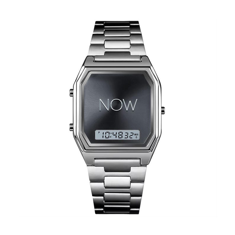 May include: A silver-toned wristwatch with a rectangular face and a linked metal band. The watch face is dark gray with the word "NOW" in the center and a digital time display showing "10:48:32".