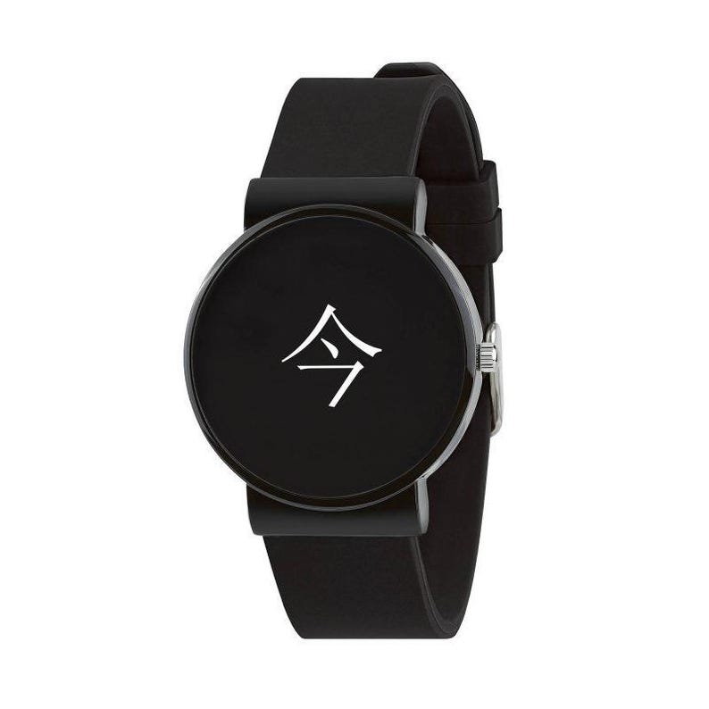 Puede incluir: Reloj de pulsera negro con esfera redonda con un s&iacute;mbolo Kanji japon&eacute;s blanco. El reloj tiene una correa negra y una hebilla plateada. La esfera del reloj tiene aproximadamente 3,8 cm de di&aacute;metro.