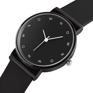 May include: A minimalist black wristwatch with a round face and a black band. The watch face features white hands and white markers at the hours. The watch has a sleek, modern design.