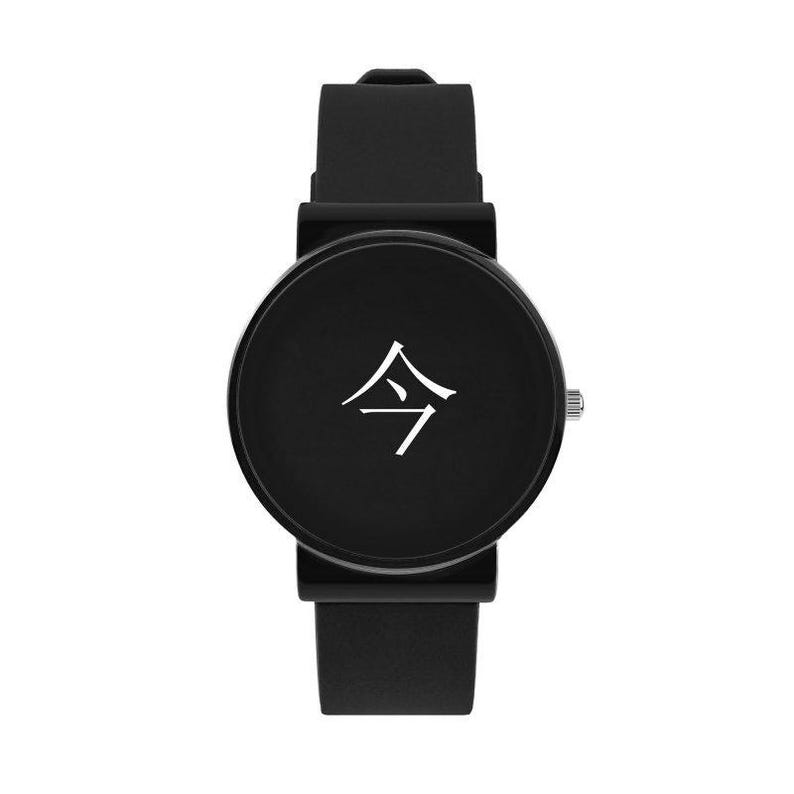 Puede incluir: Reloj de pulsera negro con esfera redonda y correa de silicona negra. La esfera del reloj presenta un s&iacute;mbolo blanco. El reloj tiene una corona plateada y una hebilla negra. Dise&ntilde;o minimalista.