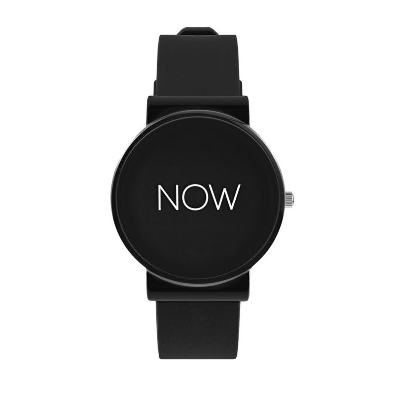 May include: A black wristwatch with a round face. The watch face displays the word "NOW" in white. The watch has a black band and a silver-colored crown.