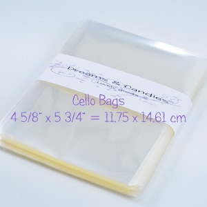 Puede incluir: Una pila de bolsas de celofán transparentes con una etiqueta que dice "Dreams & Candies Lovely Goods Cello Bags 4 5/8" x 5 3/4" = 11.75 x 14.61 cm".