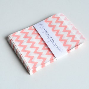 Puede incluir: Un montón de bolsas de papel de color rosa y blanco con estampado de chevron con una etiqueta que dice "Dreams & Candies, lovely goodies".