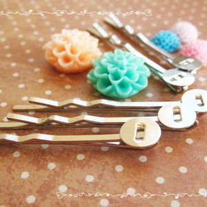 May include: Four silver hair clips with decorative flower accents. The flowers are in shades of pink, peach, and turquoise.