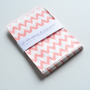 Puede incluir: Un paquete de bolsas de papel con estampado de chevron rosa y blanco con una etiqueta que dice "Dreams & Candies Lovely Goods".