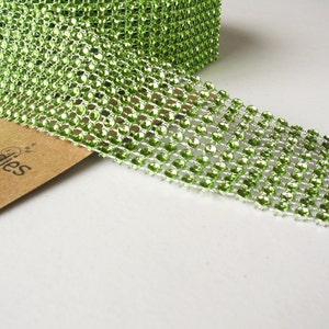 May include: Green rhinestone ribbon with a shiny finish. The ribbon is made of small, round rhinestones that are set in a grid pattern.