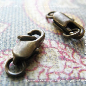 May include: Two antique silver-toned lobster claw clasps. The clasps are made of metal and have a shiny finish.