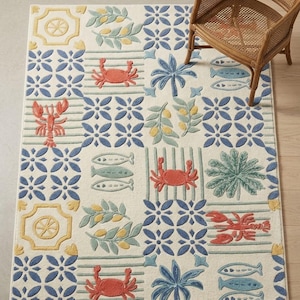 May include: A rectangular rug with a marine theme. The rug has a cream background with blue floral and striped patterns. It features images of crabs, fish, palm trees, and lemons. A wicker chair is in the background.