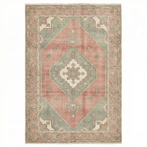 May include: A rectangular rug with a central diamond pattern in muted coral, sage green, and cream. The rug features a detailed border with floral and geometric motifs, creating a vintage or antique aesthetic. The rug's dimensions are not visible.