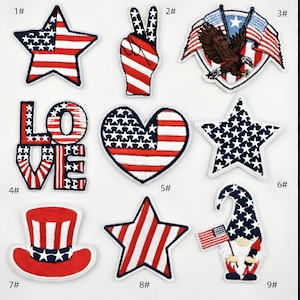 以下が含まれることがあります： アメリカ国旗のデザインが施された愛国的なパッチのコレクション。星型、ピースサイン、旗を持つワシ、"LOVE"の文字、ハート、シルクハット、旗を持ったノームが含まれています。