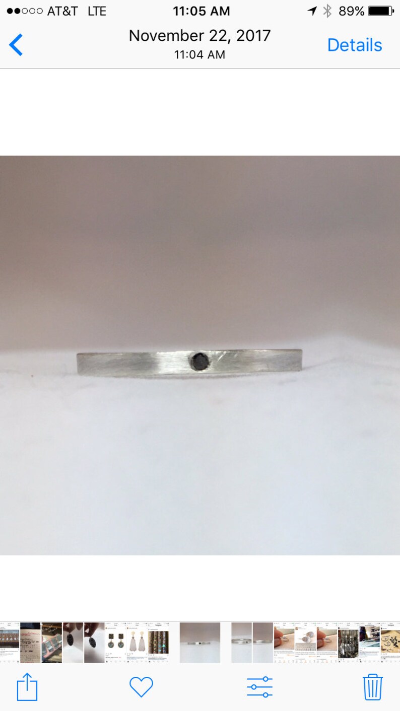 May include: A silver band with a single black diamond set in the center.