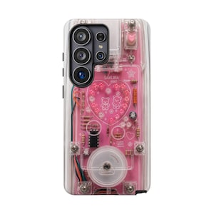 May include: A clear phone case featuring a pink circuit board design with a heart-shaped arrangement of beads, two bear illustrations, and the text SAKURA RESET. The design includes electronic components like resistors and wires visible underneath.
