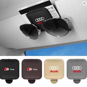 Puede incluir: Organizador de visera de coche negro con el logotipo de Audi, que sostiene gafas de sol y una tarjeta. Debajo, cuatro organizadores de visera adicionales en negro, marrón, beige y gris, cada uno con un logotipo de Audi o S line diferente.