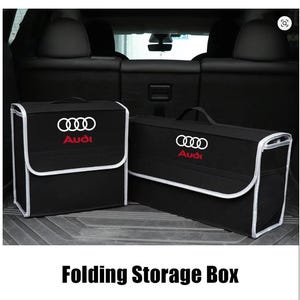 May include: Two black folding storage boxes with white trim and the Audi logo in white and red. The boxes have handles and are designed for car trunk organization. The text "Folding Storage Box" is at the bottom of the image.