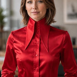 May include: A striking red satin blouse with a distinctive high collar and long sleeves. The blouse has a button-down design and a fitted silhouette. This elegant top is suitable for formal or business wear. The fabric has a luxurious sheen.