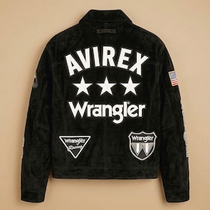 May include: Black suede jacket with the text "AVIREX" above three white stars and the word "Wrangler". Features patches with the Wrangler logo and an American flag. A classic, stylish jacket.