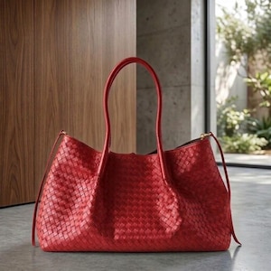 Op de afbeelding: Een rode geweven leren tote bag met lange handvatten. De tas heeft een rechthoekige vorm en een ruim interieur. De handvatten zijn gebogen en lopen omhoog. De tas is gemaakt van een geweven materiaal en heeft een gladde textuur.
