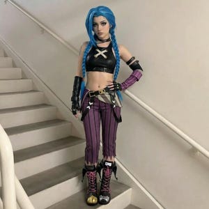 May include: A cosplay outfit comprising a black crop top with an X design, purple and black striped trousers, and black boots with pink laces. The character has blue braided hair and is on a staircase.