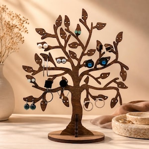 May include: A wooden earring display stand shaped like a tree, showcasing various earrings. The brown tree has a circular base. The earrings are of different styles and colours, including pearl, silver hoop, and gemstone earrings.