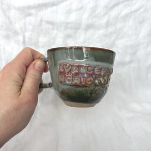 Może przedstawiać: Ręcznie robiony drewniany znak z napisem "Welcome" w fantazyjnej czcionce. Znak pomalowany na biało ma postarzaną powierzchnię i kwiatowy wzór w odcieniach różu i zieleni. Przeznaczony do użytku wewnątrz i na zewnątrz.