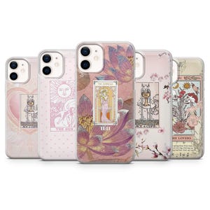 May include: Five clear smartphone cases featuring tarot card designs. The cases display various illustrations including The Sun, The Empress with 11:11 text, Ace of Cups, and The Lovers. The designs incorporate floral motifs, pink and gold tones.