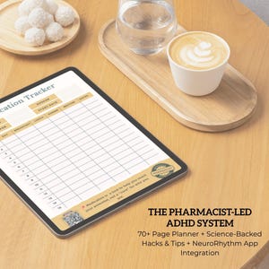 May include: A digital tablet displaying a medication tracker, a smartphone with the NeuroRhythm app, and a stylus on a wooden table. The tablet has a grid for tracking medication details. The image also includes a cup of coffee and a plate of white treats.