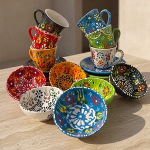 May include: A white ceramic mug with a black handle and the text "But First, Coffee" in a handwritten style. The mug is on a white surface. The mug is approximately 4 inches tall.