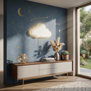 Könnte beinhalten: Ein modernes Wohnzimmer mit einer blauen Wand, die mit goldenen Sternbild-Aufklebern und einer wolkenförmigen Leuchte verziert ist. Ein Holzschrank mit neutraler Front beherbergt dekorative Gegenstände, darunter eine geometrische Glasskulptur und eine Vase mit getrockneten Pflanzen.