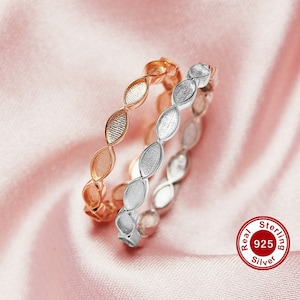 May include: Two sterling silver rings with a leaf design. The ring on top is rose gold and the ring on the bottom is silver. The rings are on a pink fabric background. Real 925 Sterling Silver.