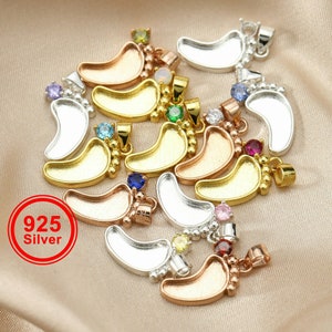 May include: A collection of 925 silver baby footprint charms with colourful gemstones. Each charm features a detailed footprint design and a small gemstone in various colours, including blue, green, pink, and red.