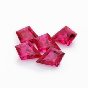 May include: Five bright pink, faceted, square-shaped gemstones with pointed corners.