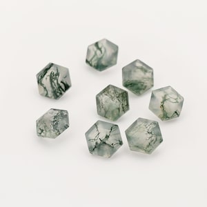 May include: Eight hexagonal green moss agate gemstones with a white background.