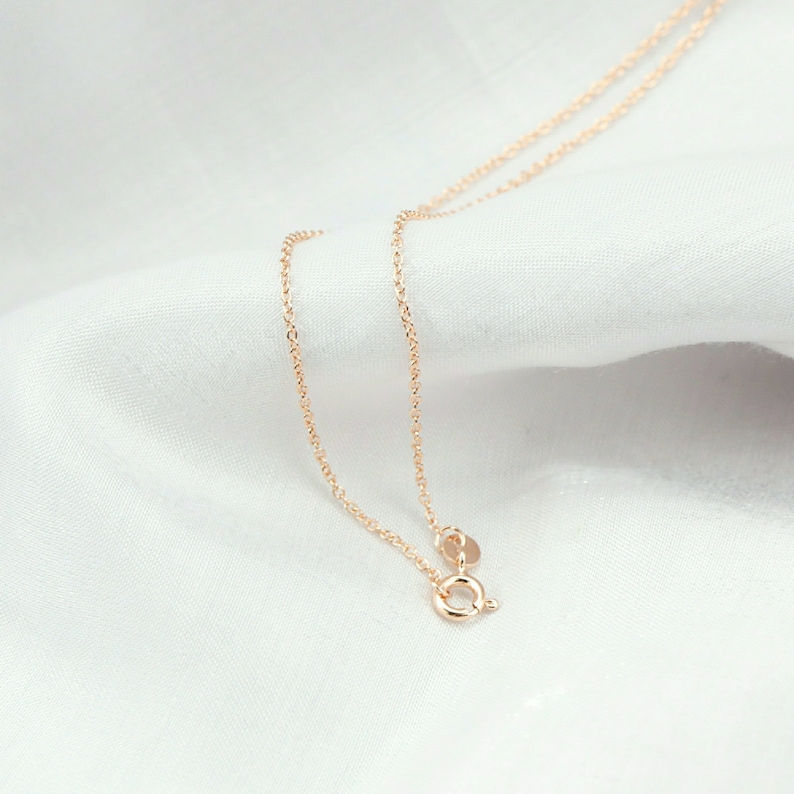 May include: A delicate gold chain necklace with a lobster clasp closure. The chain is made of a fine, linked design.