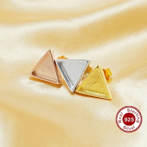 May include: Three triangle-shaped earrings in rose gold, silver, and gold. The earrings are on a light beige fabric background. Real 925 Sterling Silver is printed on a red circle.