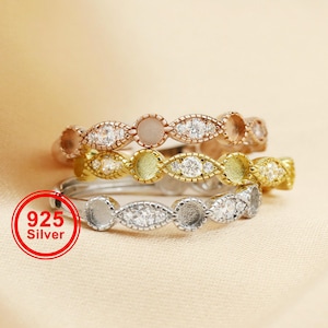 Puede incluir: Tres anillos de plata con diferentes acabados: oro rosa, oro y plata. Cada anillo presenta un patrón repetido de pequeñas piedras preciosas transparentes y engastes abiertos. Los anillos se muestran sobre una superficie de color beige claro. Un círculo rojo con el texto "925 Silver" está en la parte inferior izquierda.