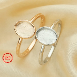 May include: Two silver rings with oval-shaped settings. The ring on the left is gold-plated. The ring on the right is silver. Both rings are 925 silver.