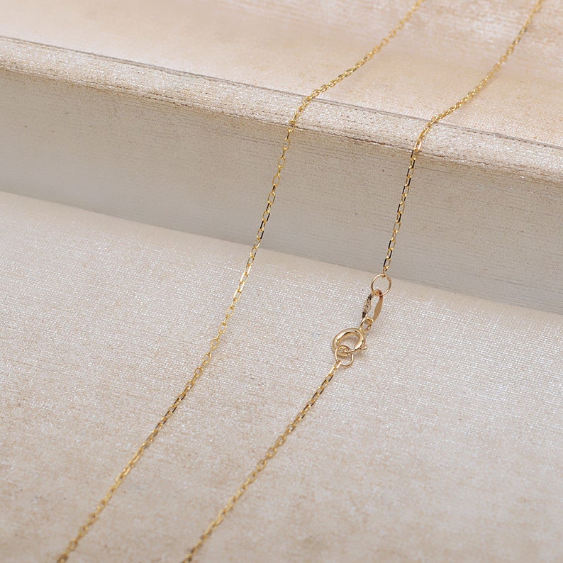 May include: A gold chain necklace with a lobster clasp closure. The chain is made of a delicate, fine-link design.