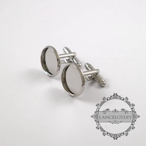 以下が含まれることがあります： 丸い透明なガラス製のインサートが付いた銀製のカフスボタンのペア。カフスボタンは金属製で、磨かれた仕上げになっています。