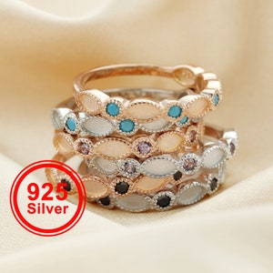 Op de afbeelding: Stapel van vijf zilveren ringen met verschillende gekleurde edelstenen. De ringen zijn versierd met een delicate, gegolfde rand. De ringen zijn gemaakt van 925 zilver.