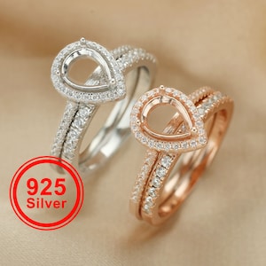 May include: Two rings with pear-shaped settings, one in silver and one in rose gold. Both rings are set with small clear stones.