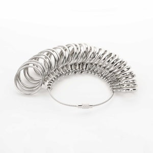 May include: A silver ring sizer with a chain and a clasp. The sizer has a series of rings of different sizes.