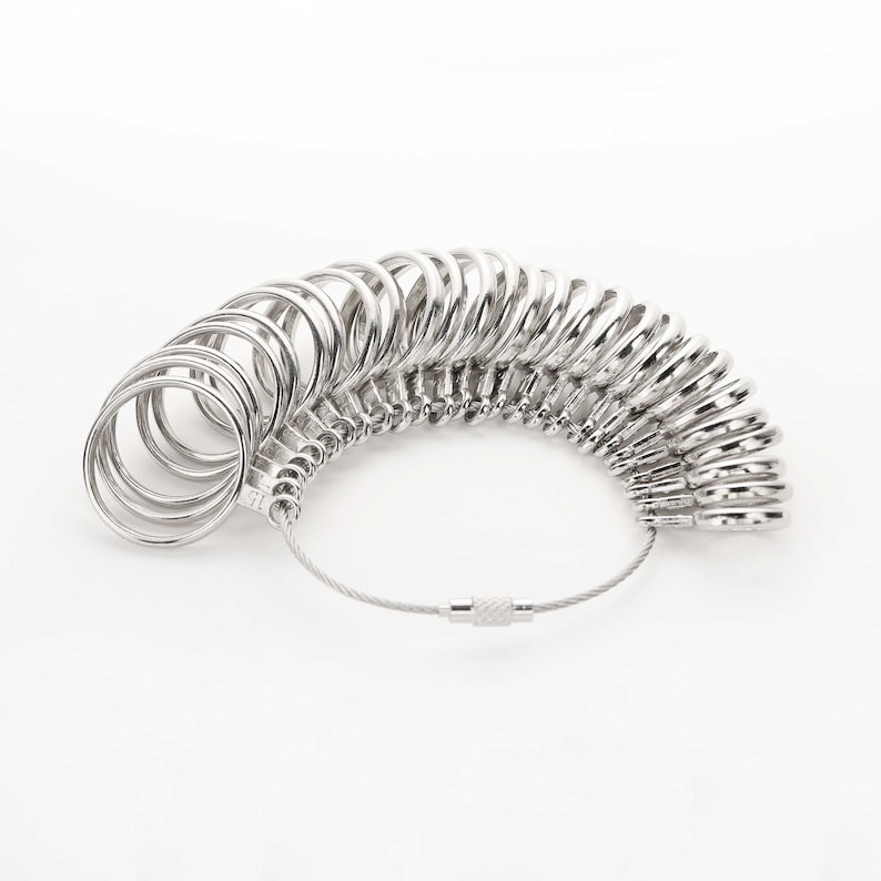 May include: A silver ring sizer with a chain and a clasp. The sizer has a series of rings of different sizes.