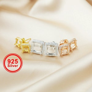 Puede incluir: Cuatro pares de engastes para pendientes de forma cuadrada con un centro transparente para piedras. Los engastes son de oro, plata y oro rosa. Los engastes están rodeados de pequeñas piedras transparentes.